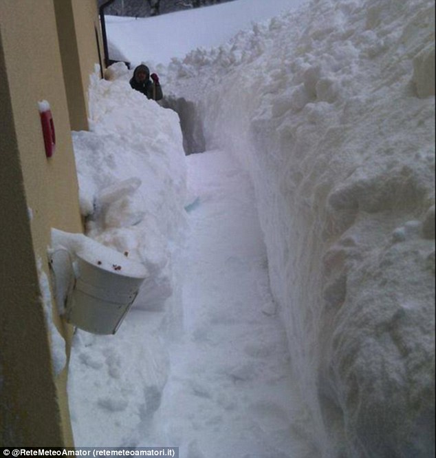 A resident clears a path from the front of their home after the snow left them trapped inside the building